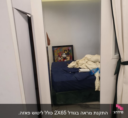 מראה גדולה על קיר לבן בחדר שינה